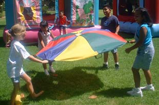 children playing a parachute at a party with Charm and Happy the clowns in Pico Rivera, CA 